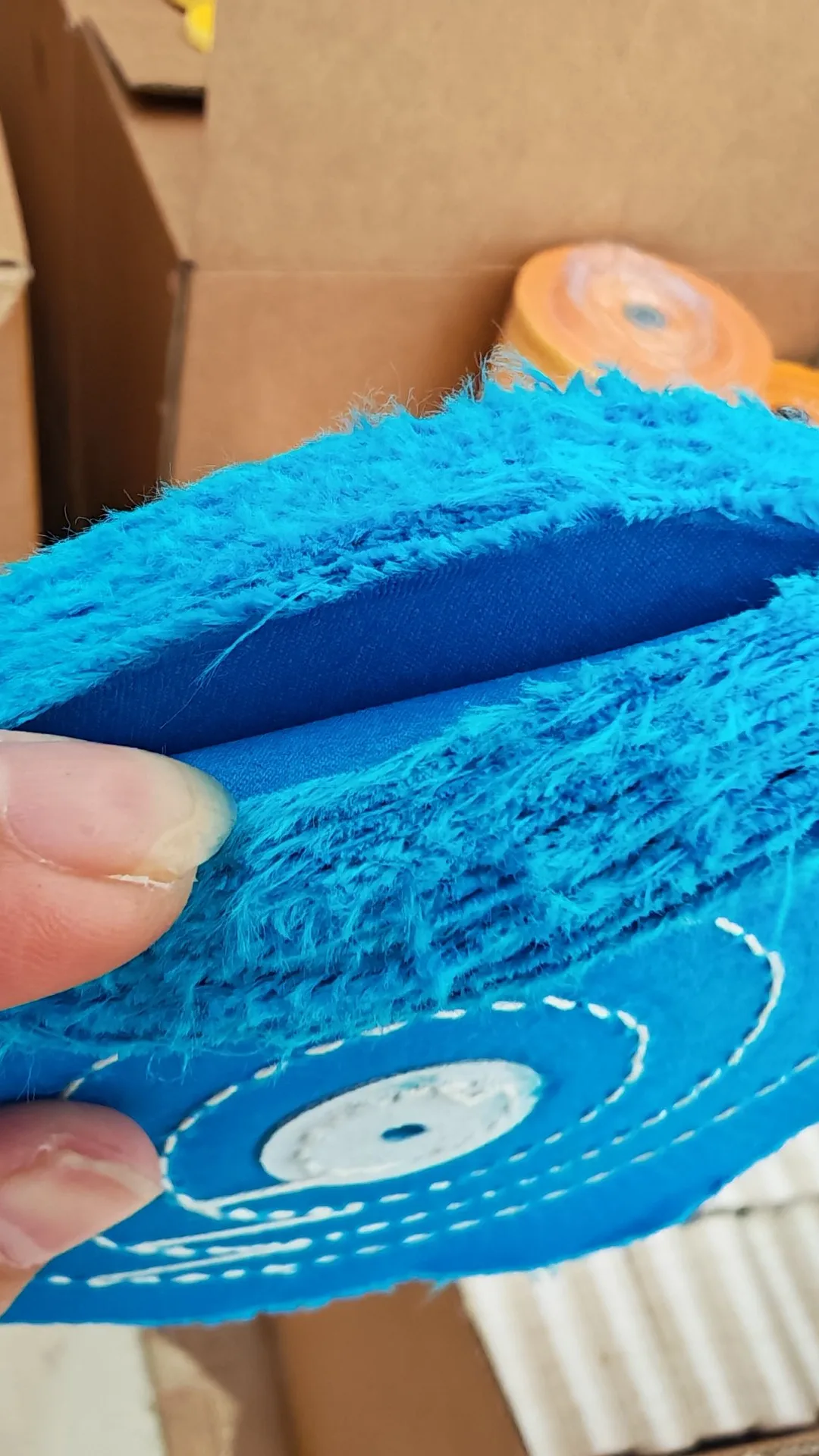 Blue cloth buffing wheel held over packed stock boxes