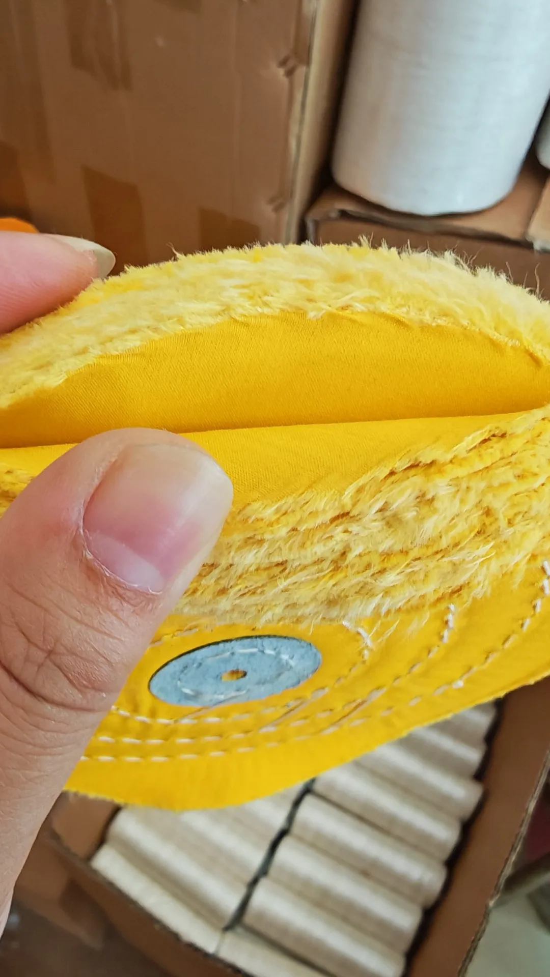 Yellow cloth buffing wheel held over packed stock boxes